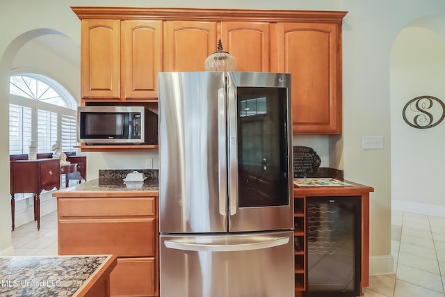 kitchen featuring beverage cooler, baseboards, stainless steel appliances, and light tile patterned flooring