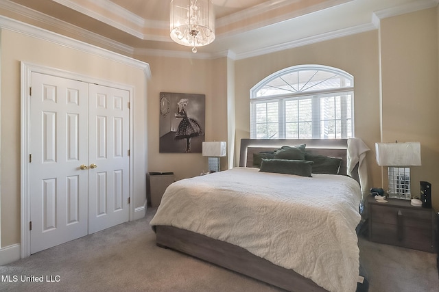 carpeted bedroom featuring ornamental molding, a raised ceiling, and a chandelier