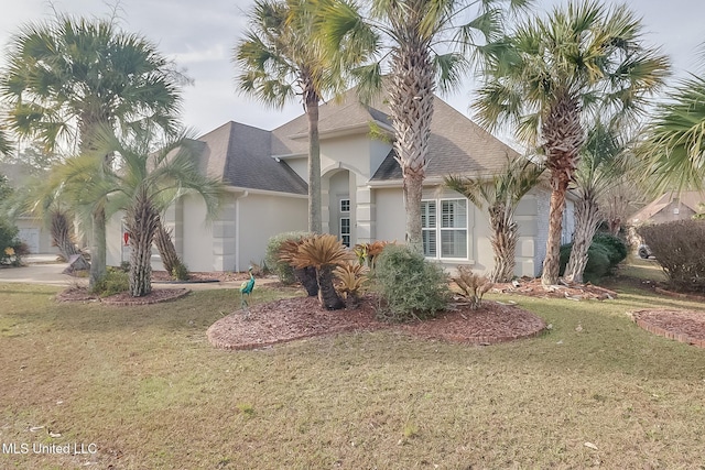 view of front of home with roof with shingles, a front lawn, and stucco siding