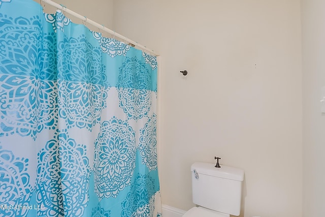 bathroom with a shower with shower curtain and toilet