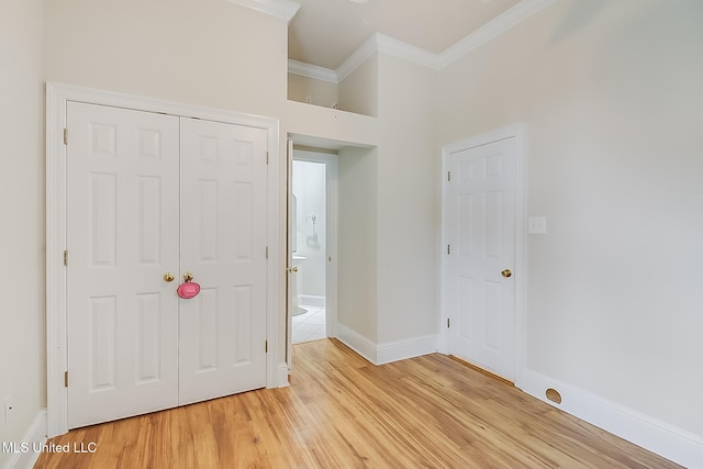 unfurnished bedroom with baseboards, light wood finished floors, a closet, and crown molding