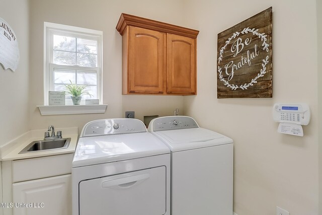 clothes washing area featuring washing machine and dryer, cabinet space, and a sink