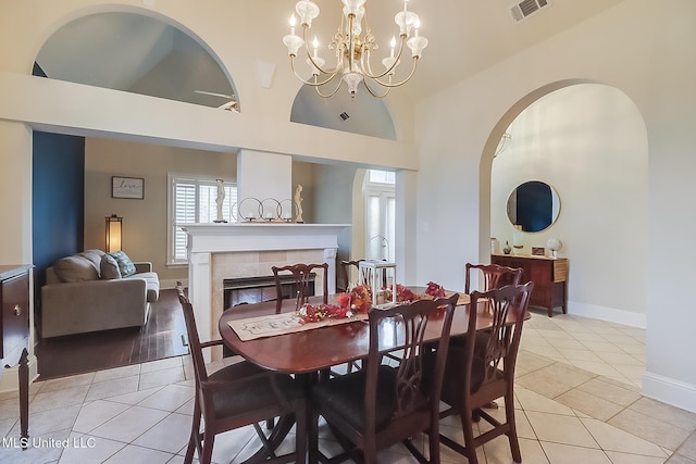 dining area with a fireplace, a notable chandelier, light tile patterned floors, visible vents, and baseboards