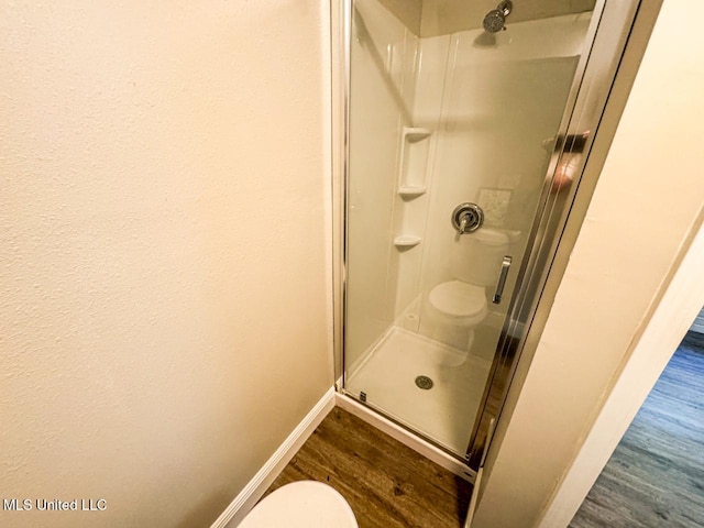 bathroom featuring hardwood / wood-style flooring, toilet, and an enclosed shower