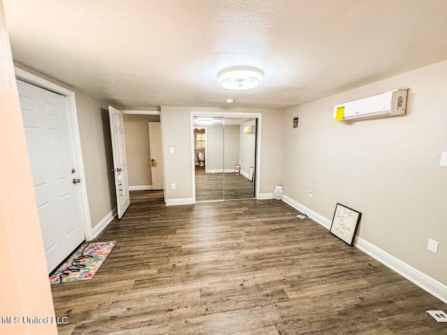 spare room with an AC wall unit, a textured ceiling, and dark hardwood / wood-style flooring