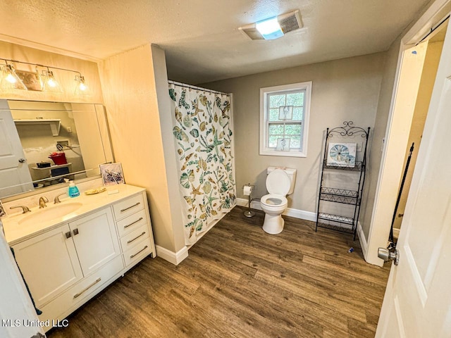 bathroom featuring wood-type flooring, vanity, a textured ceiling, and toilet