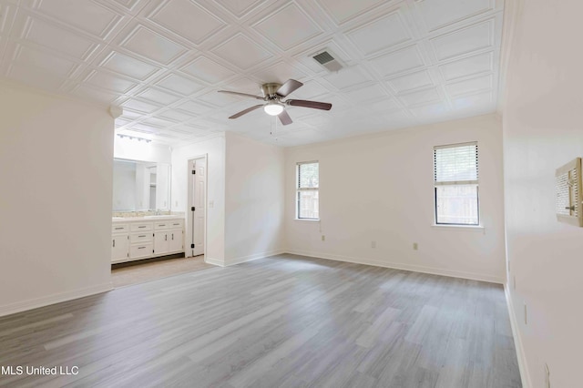 unfurnished bedroom featuring baseboards, light wood-type flooring, an ornate ceiling, and visible vents