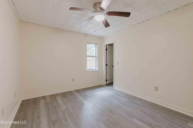 empty room featuring ceiling fan, baseboards, and wood finished floors