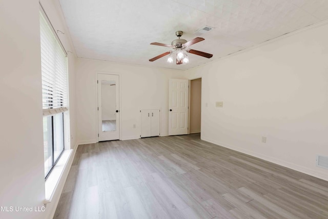 spare room featuring ceiling fan, baseboards, visible vents, and wood finished floors
