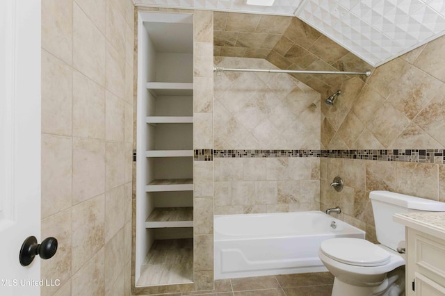 bathroom featuring toilet, tile walls, vanity, built in shelves, and shower / bathing tub combination
