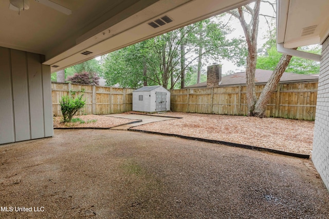 view of yard with a shed, ceiling fan, a fenced backyard, and a patio