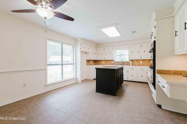 kitchen with a ceiling fan, a center island, light tile patterned flooring, backsplash, and light countertops
