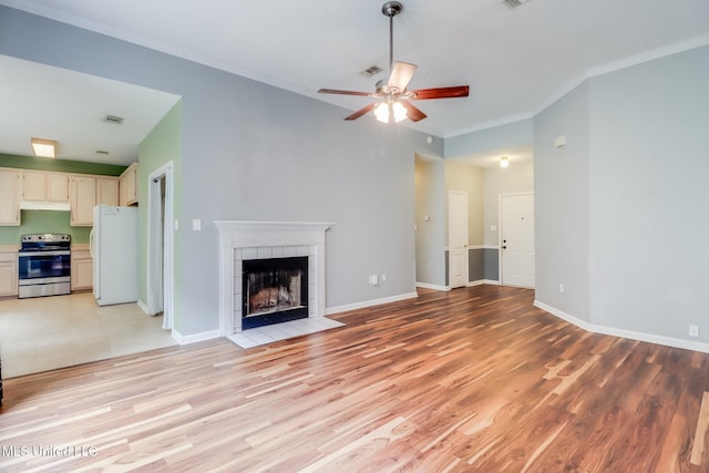 16383 Clearwater Cir, Gulfport, MS 39503 - unfurnished living room featuring ornamental molding, ceiling fan, a tile fireplace, and light wood finished floors