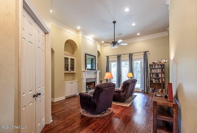 living room featuring ceiling fan, crown molding, and dark wood-type flooring