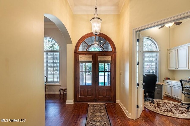 entryway with crown molding, a towering ceiling, dark wood-type flooring, and french doors