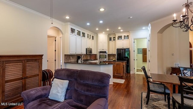 kitchen featuring backsplash, white cabinets, a notable chandelier, and appliances with stainless steel finishes