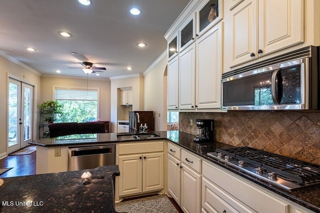 kitchen with sink, dark stone countertops, white cabinetry, kitchen peninsula, and stainless steel appliances