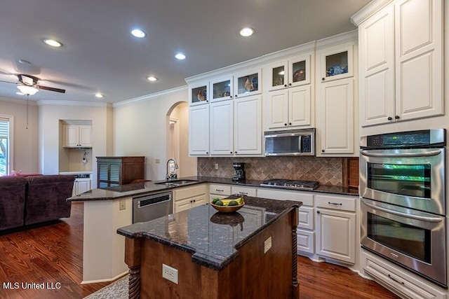 kitchen featuring a center island, backsplash, white cabinetry, kitchen peninsula, and stainless steel appliances