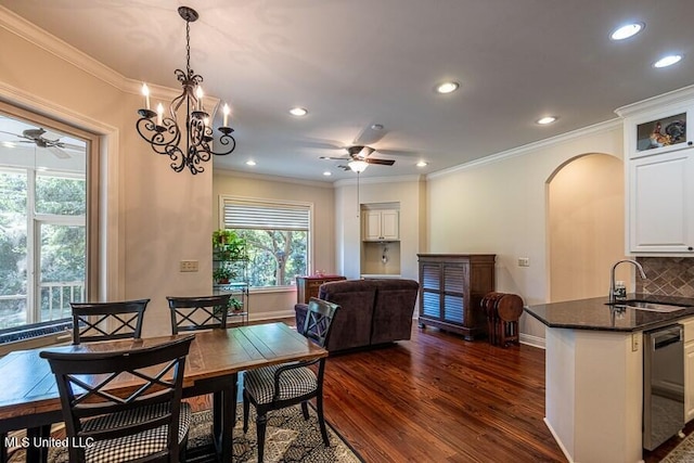 dining room featuring dark hardwood / wood-style flooring, sink, ceiling fan with notable chandelier, and ornamental molding