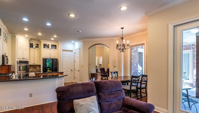 kitchen featuring hanging light fixtures, an inviting chandelier, black fridge, dark hardwood / wood-style flooring, and white cabinets