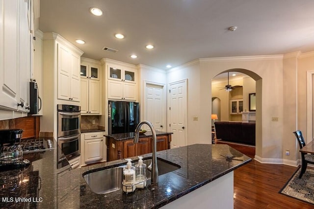 kitchen featuring dark stone counters, white cabinets, black refrigerator, sink, and stainless steel double oven