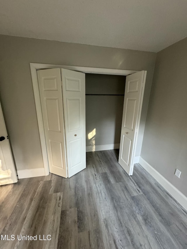 unfurnished bedroom featuring dark wood-type flooring and a closet