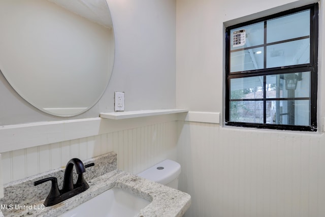 bathroom featuring vanity, toilet, and wood walls