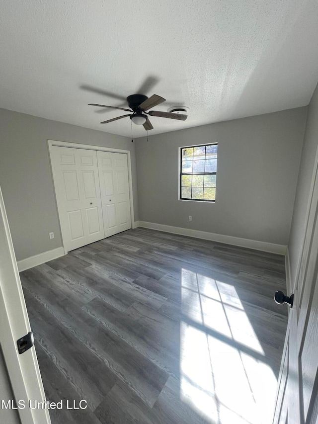 unfurnished bedroom with dark hardwood / wood-style flooring, a textured ceiling, a closet, and ceiling fan