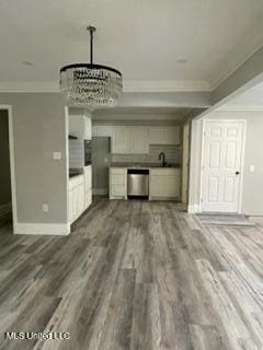 unfurnished living room with ornamental molding, dark hardwood / wood-style floors, sink, and a notable chandelier