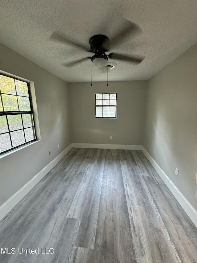 empty room with ceiling fan, light hardwood / wood-style floors, and a textured ceiling