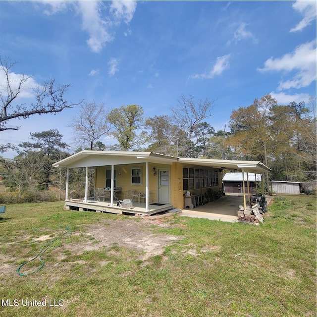 back of house featuring a lawn, an attached carport, and a porch