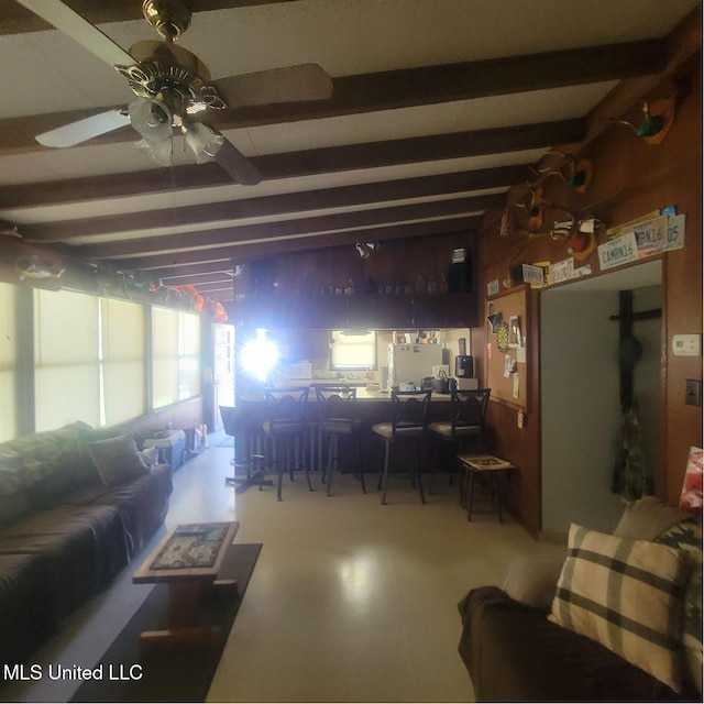 living room featuring beamed ceiling and ceiling fan
