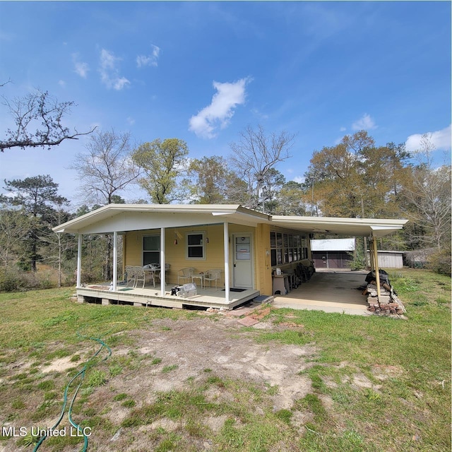 rear view of property featuring a lawn, a wooden deck, an attached carport, and driveway