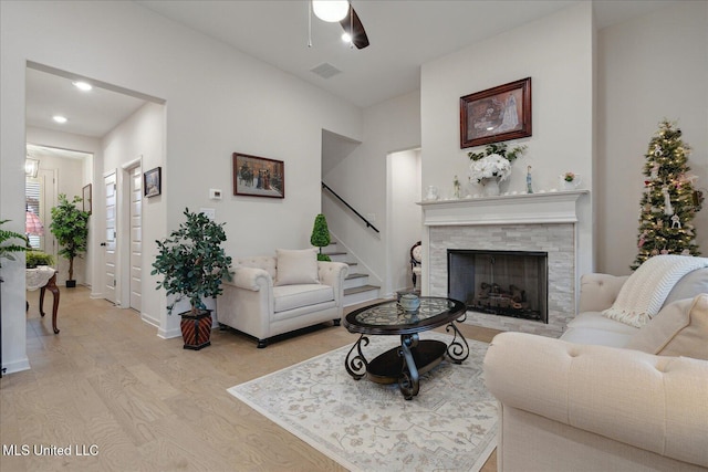 living room with ceiling fan, a fireplace, and light hardwood / wood-style flooring