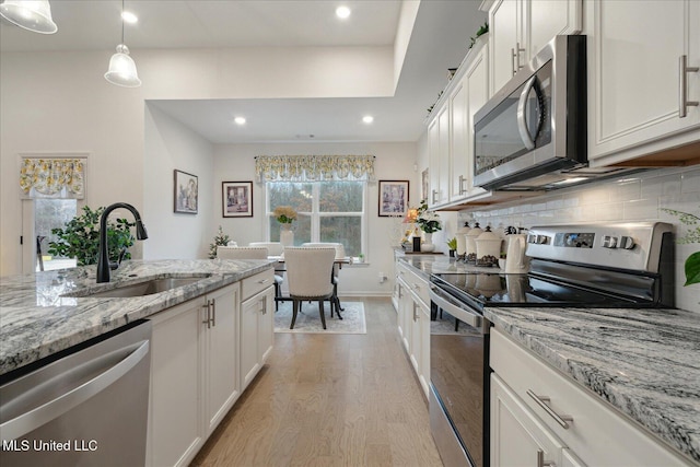 kitchen featuring appliances with stainless steel finishes, backsplash, sink, pendant lighting, and white cabinets