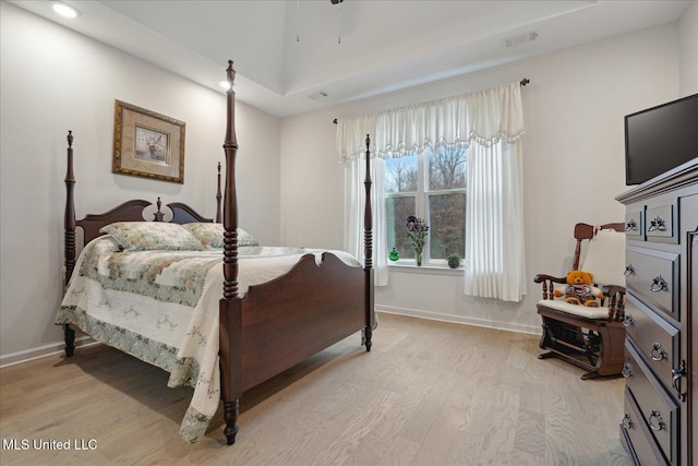 bedroom featuring a raised ceiling and light wood-type flooring