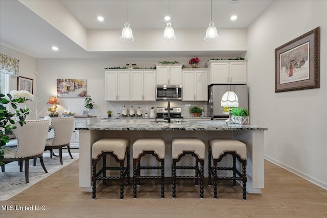 kitchen featuring tasteful backsplash, dark stone counters, stainless steel appliances, white cabinetry, and hanging light fixtures