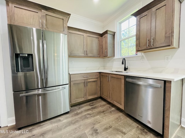 188 E Byhalia Creek Farms Rd, Byhalia, MS 38611 - kitchen featuring appliances with stainless steel finishes, ornamental molding, a sink, light wood finished floors, and light stone counters