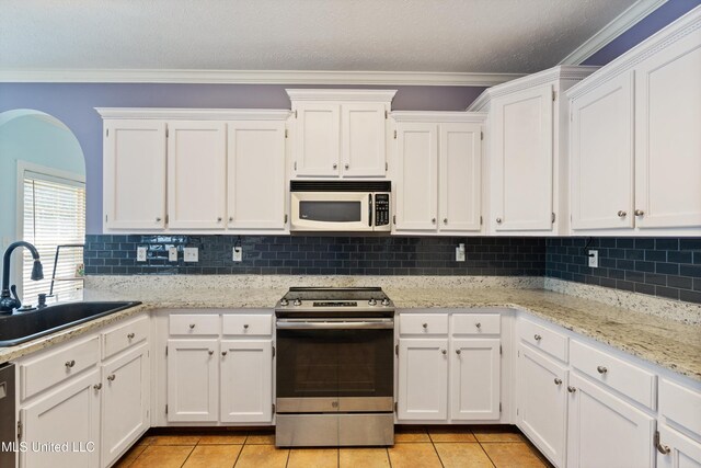 12857 Arbor Dr, Olive Branch, MS 38654 - kitchen featuring stainless steel appliances, white cabinetry, light tile patterned floors, backsplash, and ornamental molding