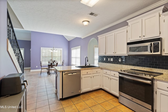 12857 Arbor Dr, Olive Branch, MS 38654 - kitchen with stainless steel appliances, a peninsula, tasteful backsplash, light tile patterned floors, and lofted ceiling