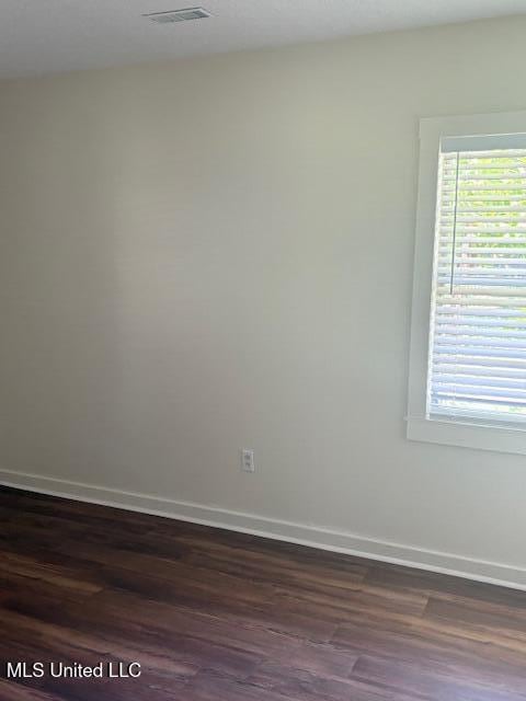 1108 W President Ave, Greenwood, MS 38930 - empty room featuring dark wood-type flooring, plenty of natural light, and baseboards
