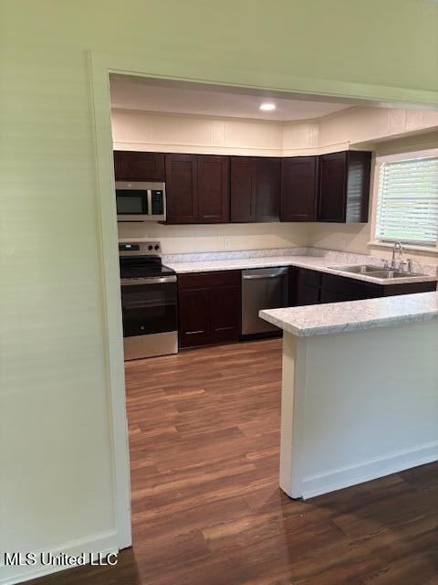 1108 W President Ave, Greenwood, MS 38930 - kitchen with appliances with stainless steel finishes, a sink, dark brown cabinetry, dark wood-style floors, and baseboards