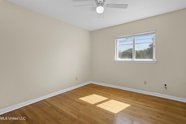 empty room featuring wood finished floors, a ceiling fan, and baseboards