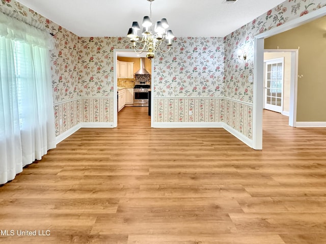 13456 John Clark Rd, Gulfport, MS 39503 - unfurnished dining area featuring wallpapered walls, a chandelier, baseboards, and light wood-style floors