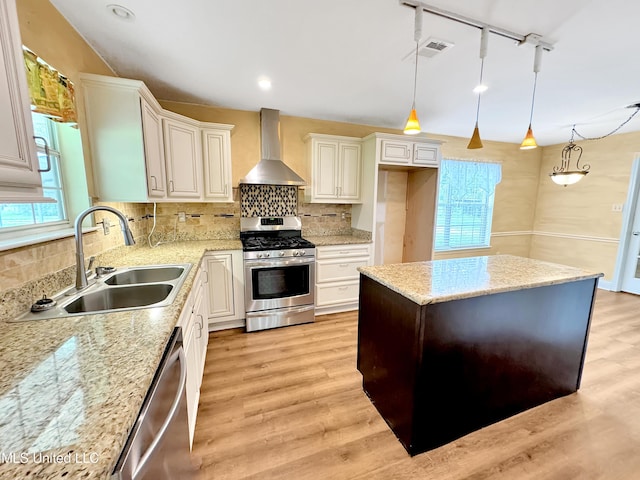 13456 John Clark Rd, Gulfport, MS 39503 - kitchen with stainless steel appliances, wall chimney exhaust hood, a sink, light wood finished floors, and decorative backsplash