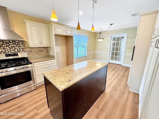 13456 John Clark Rd, Gulfport, MS 39503 - kitchen featuring stainless steel gas stove, wall chimney exhaust hood, light wood-style floors, and tasteful backsplash