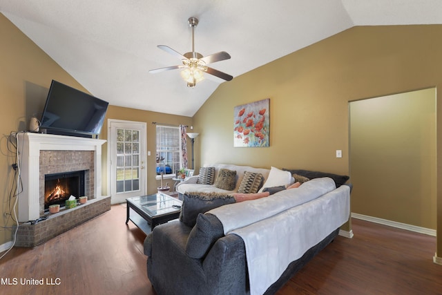 living room with a brick fireplace, dark wood-type flooring, ceiling fan, and vaulted ceiling