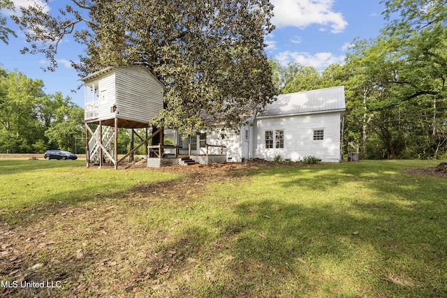 rear view of house featuring a lawn, a wooden deck, metal roof, and stairs