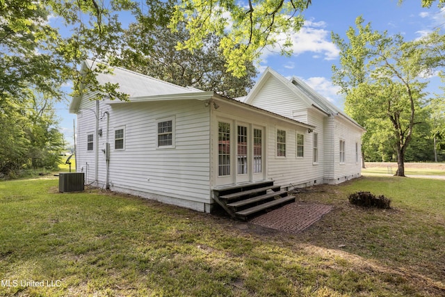 rear view of property with metal roof, a yard, and entry steps