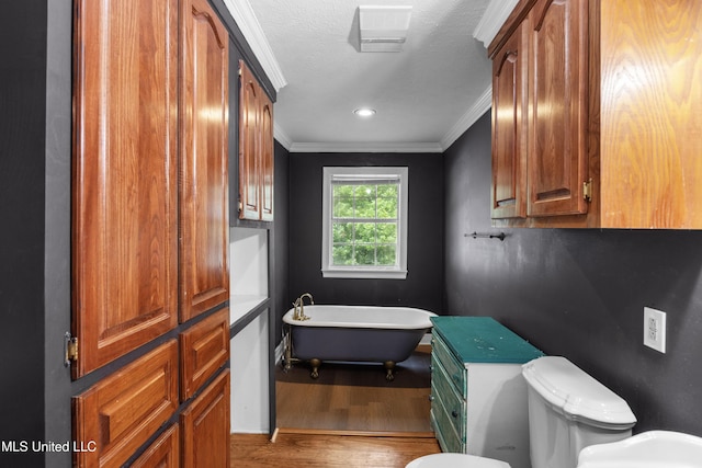 full bath featuring crown molding, a freestanding tub, wood finished floors, baseboards, and toilet